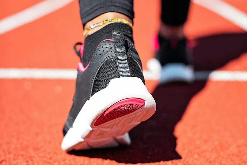 Close-up of a runner’s sneaker pushing off from an orange running track.